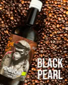 Eine Flasche mit einem Etikett, das einen Affen zeigt, liegt auf Kaffeebohnen. Rechts steht der Text "BLACK PEARL".