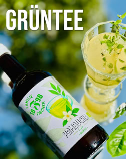 Flasche mit grünem Etikett und Glas mit grünem Getränk, dekoriert mit Kräutern, vor unscharfem Hintergrund; Text "GRÜNTEE" oben links.