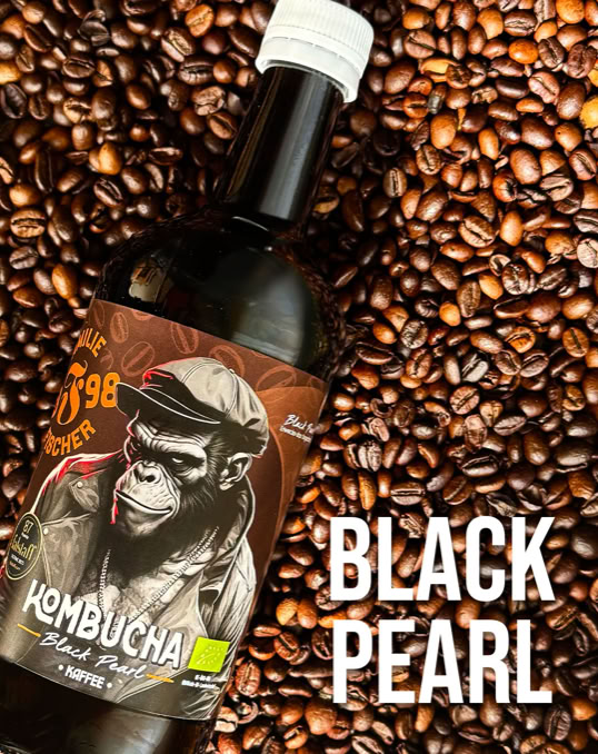 Eine Flasche mit einem Etikett, das einen Affen zeigt, liegt auf einer Oberfläche aus Kaffeebohnen. Rechts unten steht der Text "BLACK PEARL".