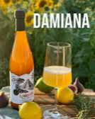 Eine Flasche und ein Glas mit gelbem Getränk auf einem Tisch, umgeben von Zitronen, Feigen und Kräutern, mit Sonnenblumen im Hintergrund. Text "DAMIANA" oben.
