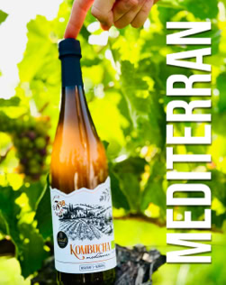 Eine Hand hält eine Weinflasche vor grünem Laub, daneben steht der Text "MEDITERRAN".