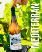 Eine Hand hält eine Weinflasche vor grünem Laub, daneben steht der Text "MEDITERRAN".